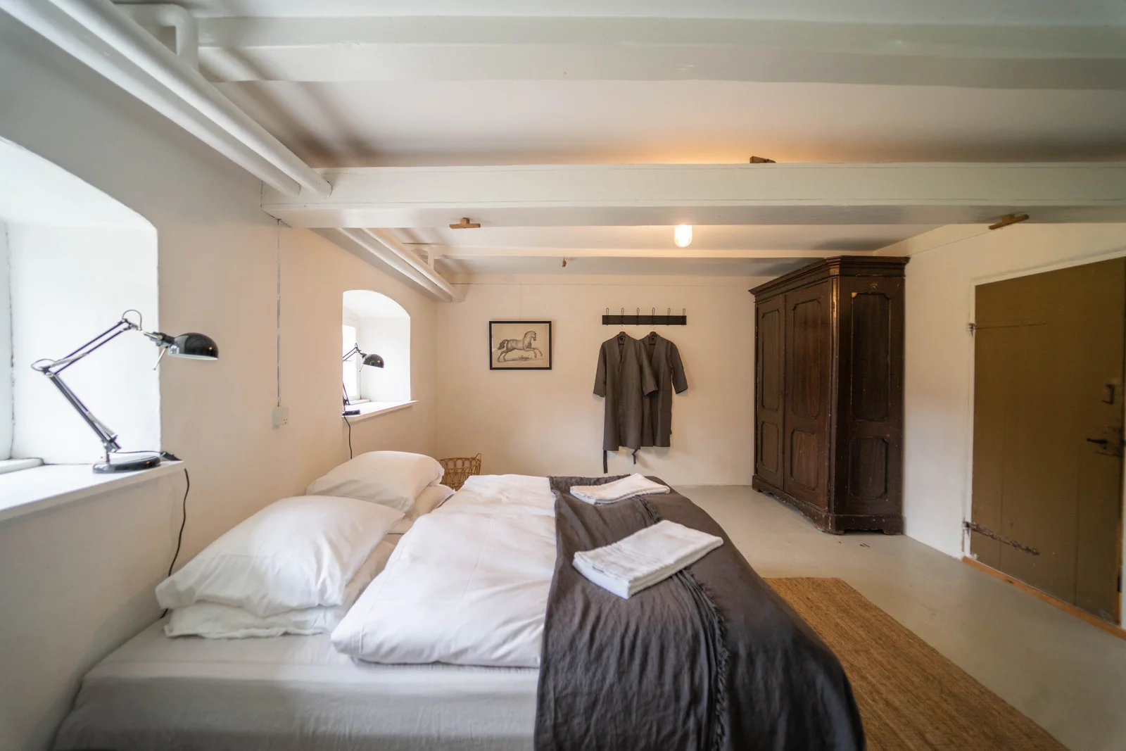 Gästezimmer mit Balkendecke, altem Kleiderschrank und Doppelbett auf Gut Agerup