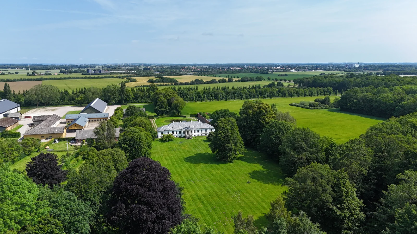 Gut Agerup aus der Luft mit dem Park, den großen Bäumen und den gestreiften Rasenflächen