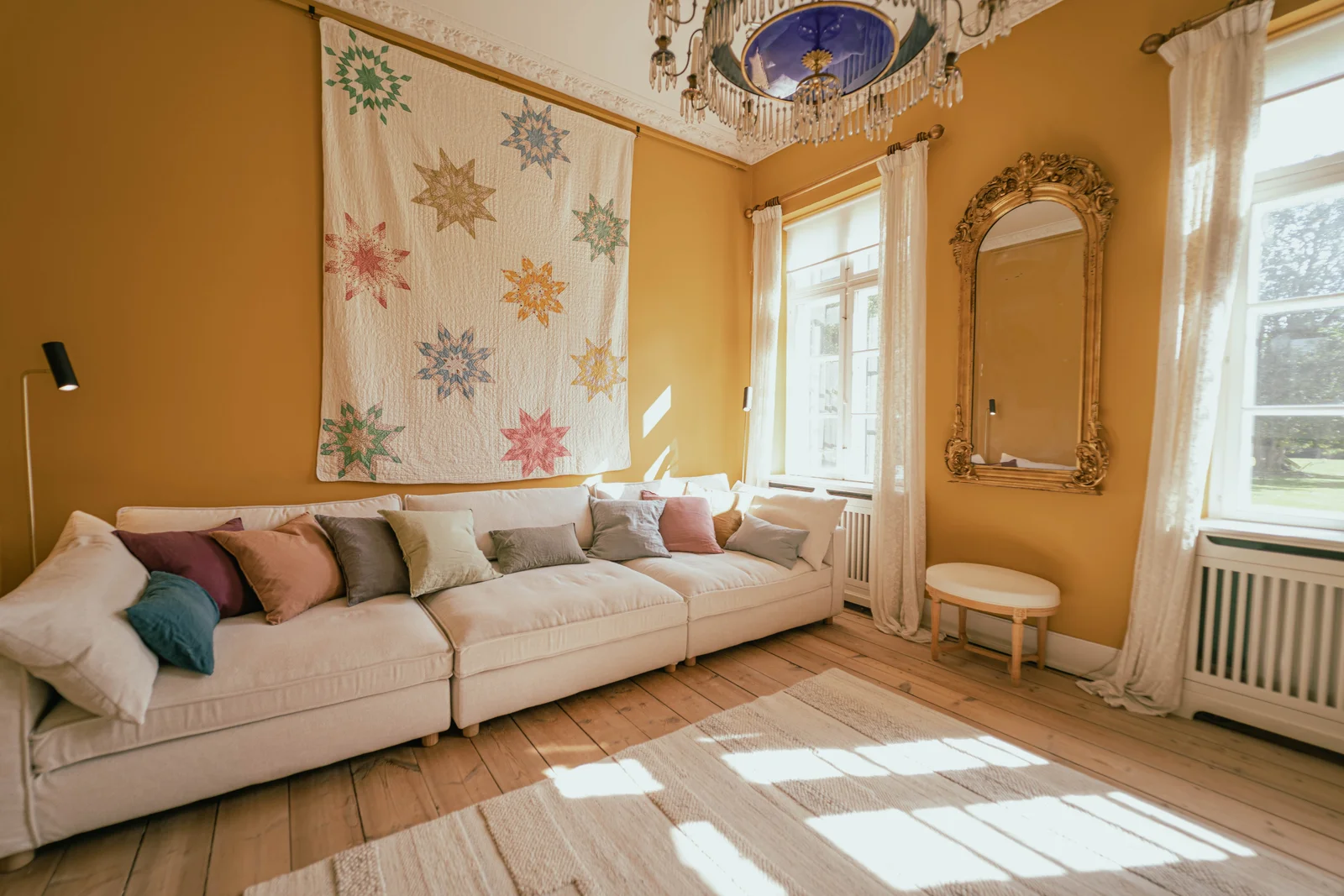 Das gelbe Zimmer von Gut Agerup mit großem Sternenquilt, langem Sofa und Kronleuchter