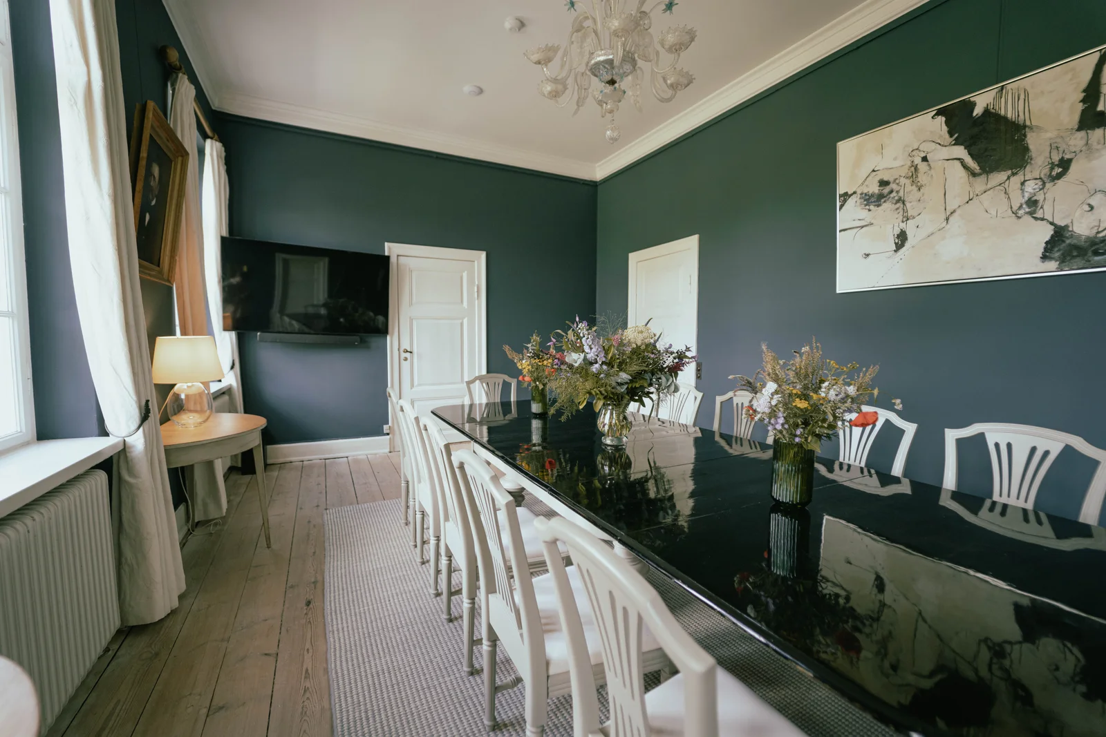 Das Speisezimmer von Gut Agerup mit Blumen entlang der Tafel und blauen Wänden