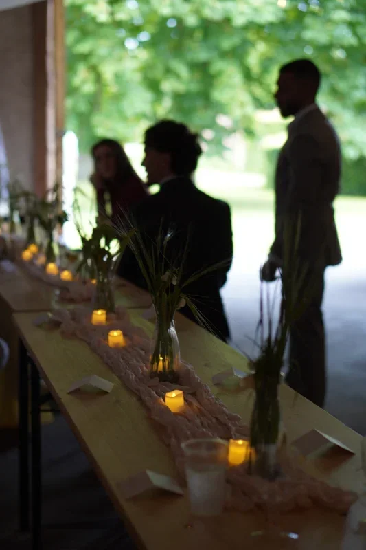 Bryllupspar ved det lange bord i laden på Agerup Gods med stearinlys og grønne vaser