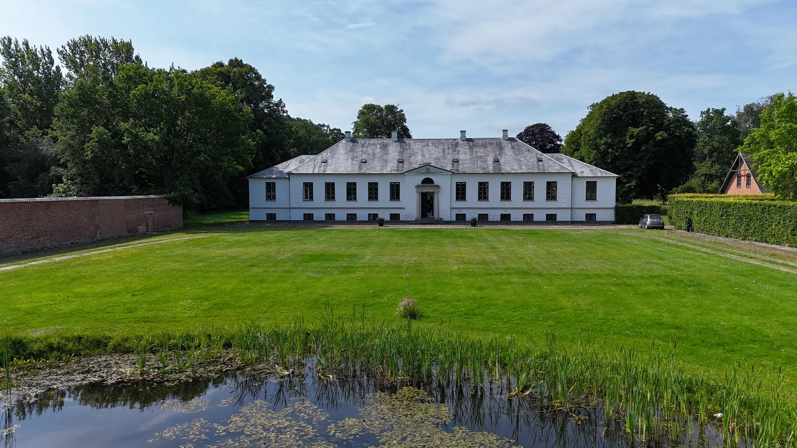 Das Herrenhaus von Gut Agerup über den Teich und die große Rasenfläche aus der Luft gesehen