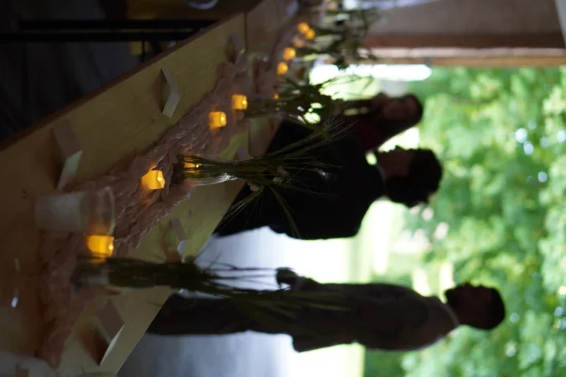 Bryllupspar ved det lange bord i laden på Agerup Gods med stearinlys og grønne vaser