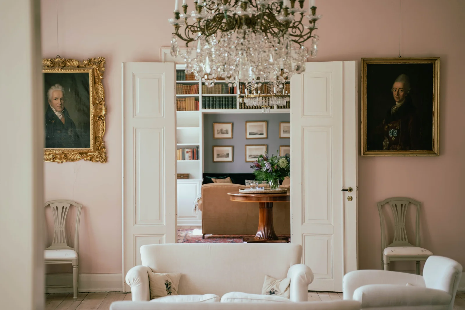 Der Salon von Gut Agerup mit Kronleuchter und Ahnenporträts, mit Blick in die Bibliothek