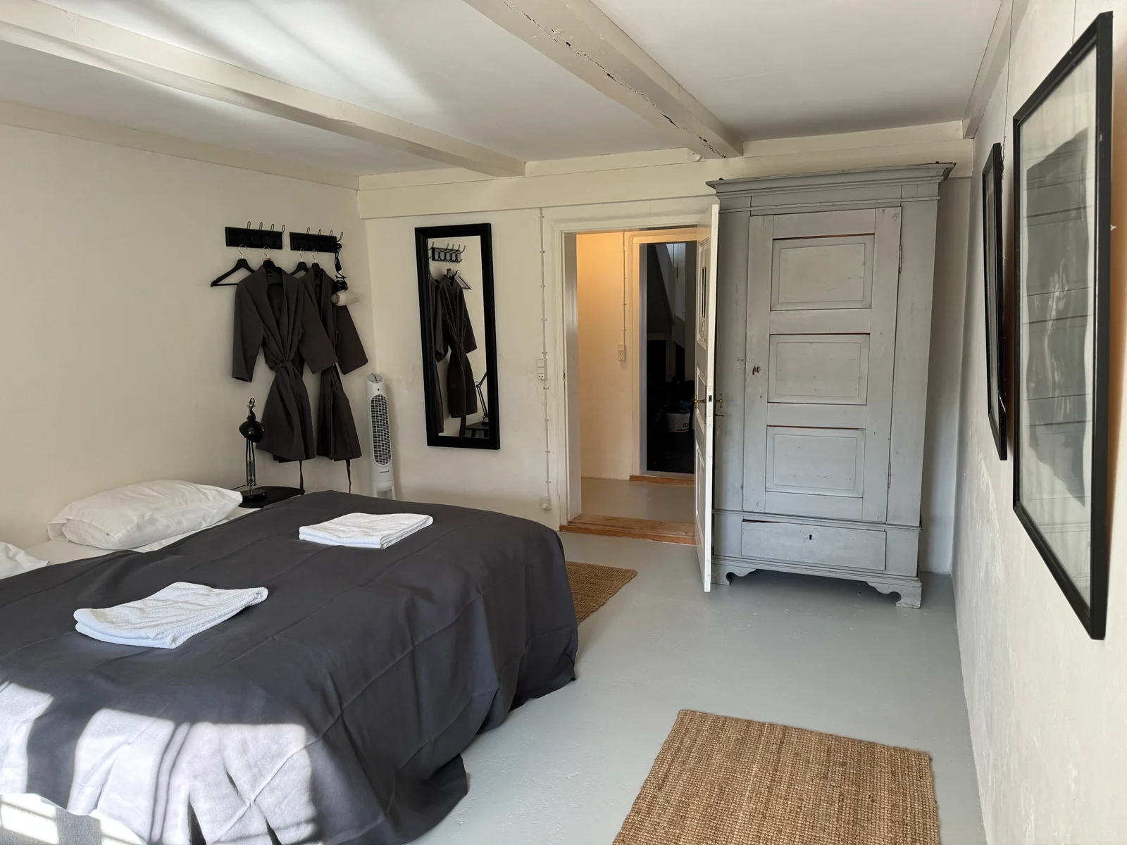 Gästezimmer mit Doppelbett, Bauernschrank und offener Tür im Herrenhaus von Gut Agerup