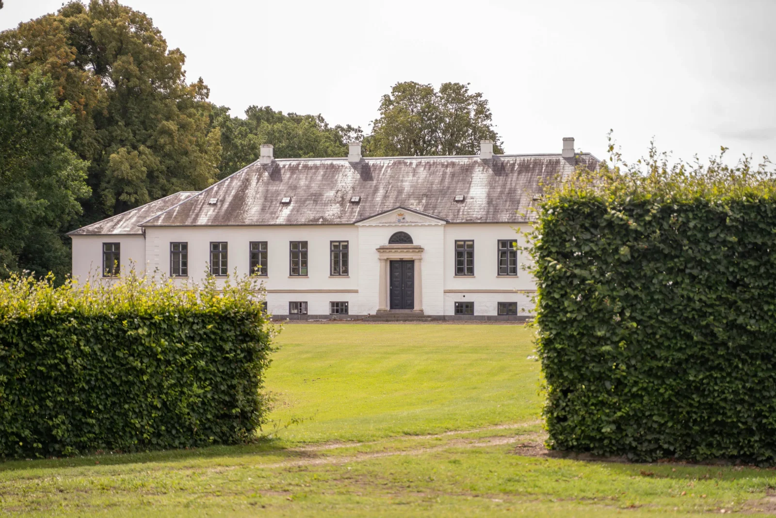 Herregården på Agerup Gods set gennem klippede hække i haven