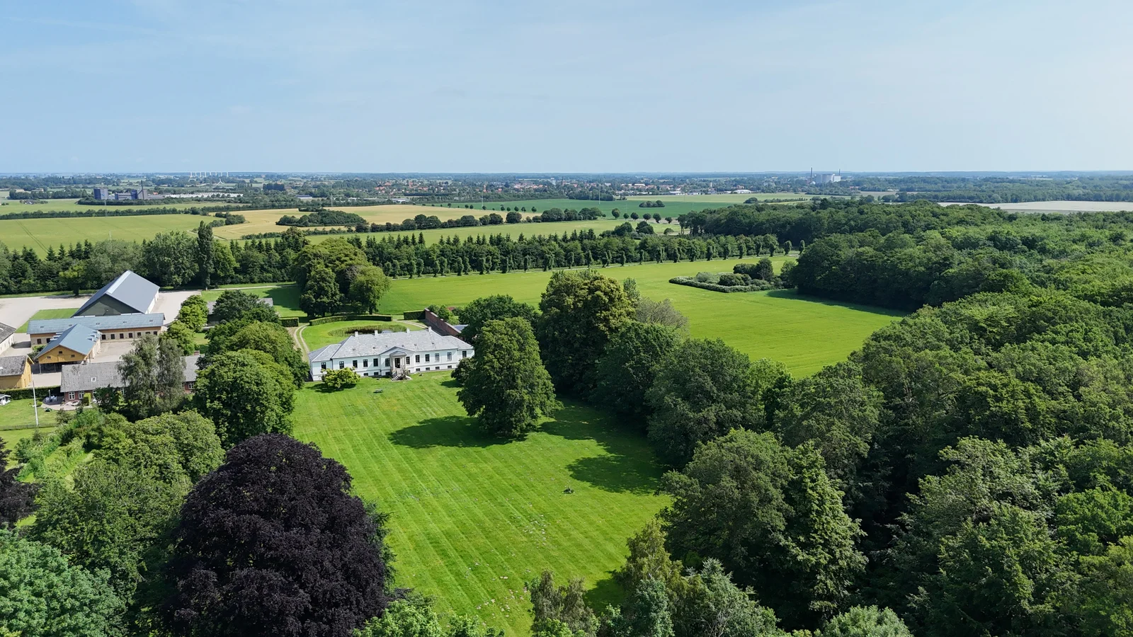 Weite Luftaufnahme von Gut Agerup, dem Park und der Landschaft bis zum Horizont