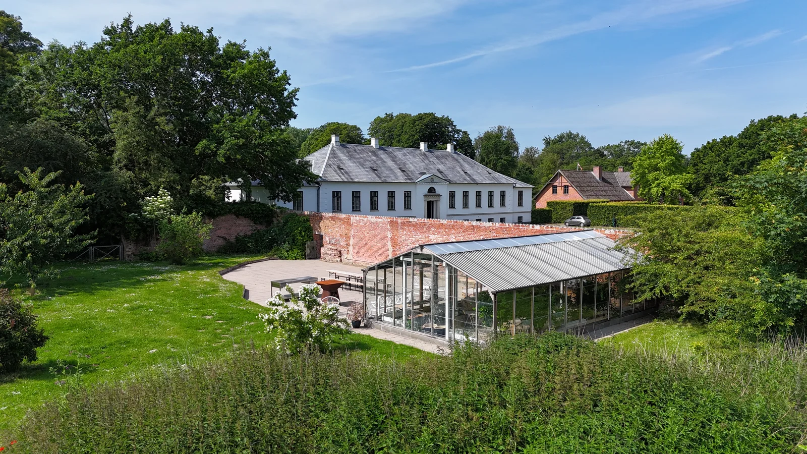 Gut Agerup aus der Luft mit dem Herrenhaus, dem ummauerten Garten und dem Glashaus an einem Sommertag