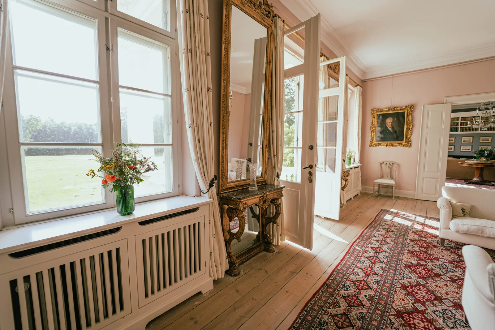 Fenster mit Blumenstrauß und vergoldetem Spiegel im Salon von Gut Agerup