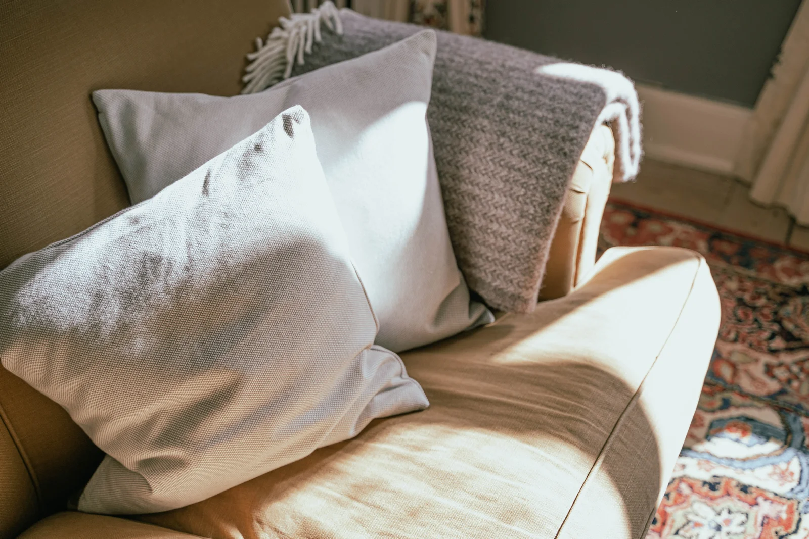 Leinenkissen und eine Decke auf einem Sofa im Sonnenlicht im Herrenhaus von Gut Agerup