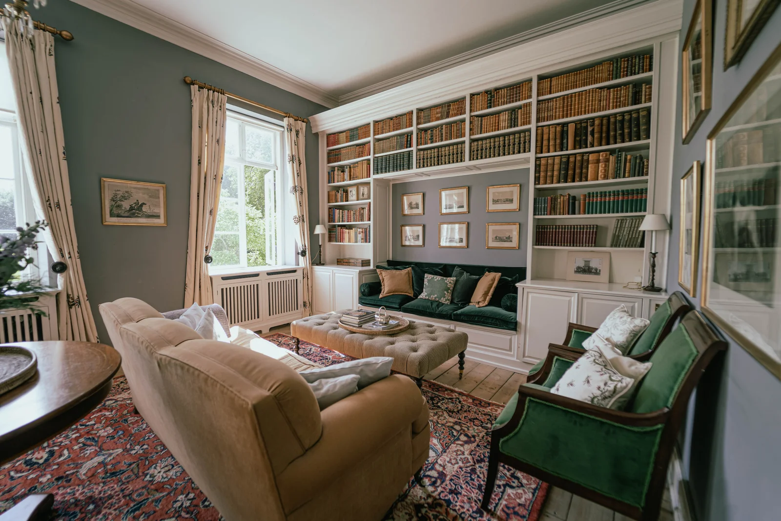 Die Bibliothek von Gut Agerup mit Sofas, grünen Sesseln und Bücherregalen