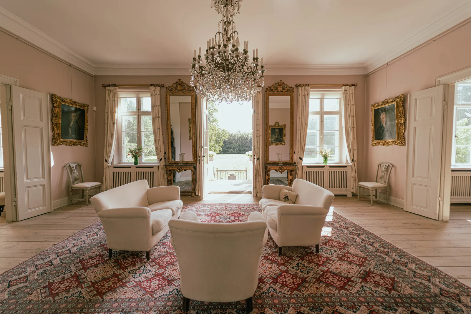 Der Festsalon im Gutshaus Agerup mit Kristalllüster, vergoldeten Spiegeln und Glastüren zum Garten