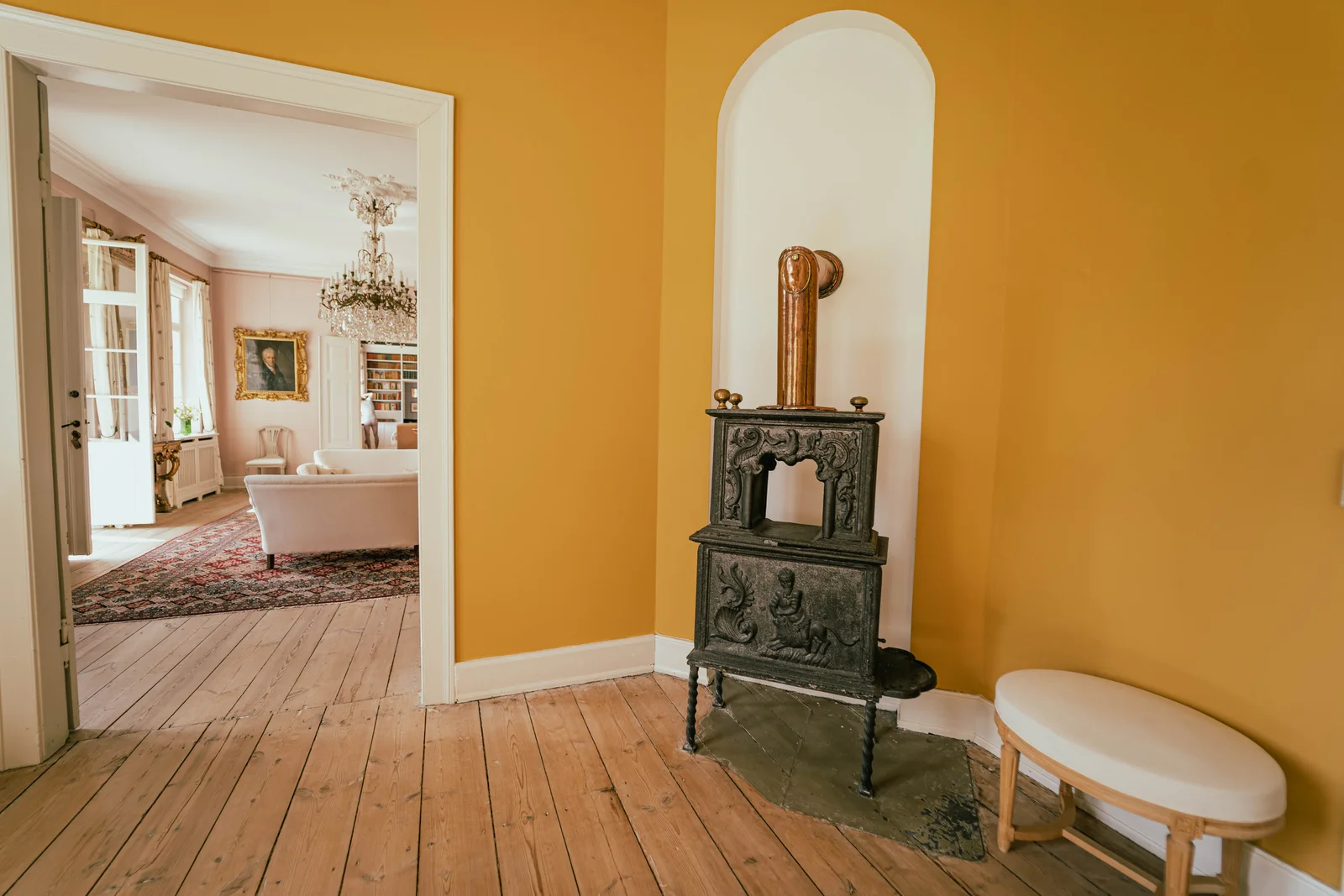 Gusseiserner Ofen in der Nische des gelben Zimmers mit Blick in den Salon von Gut Agerup