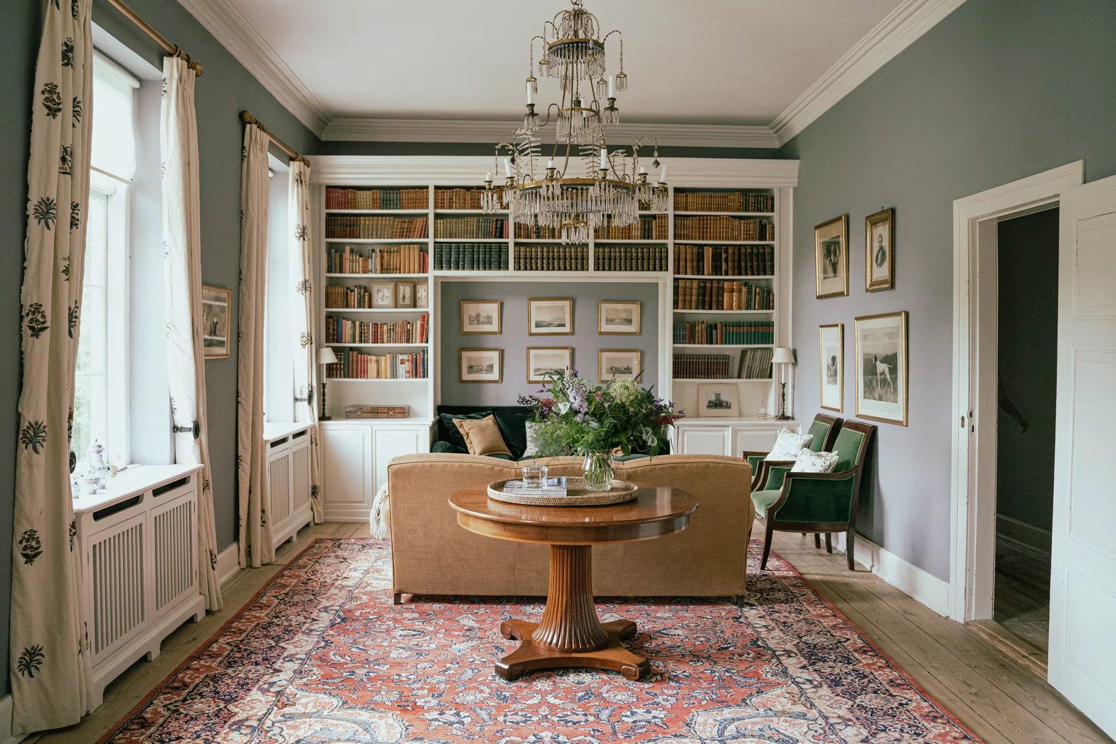 Die Bibliothek von Gut Agerup mit Kronleuchter, Teppich und raumhohen Bücherregalen
