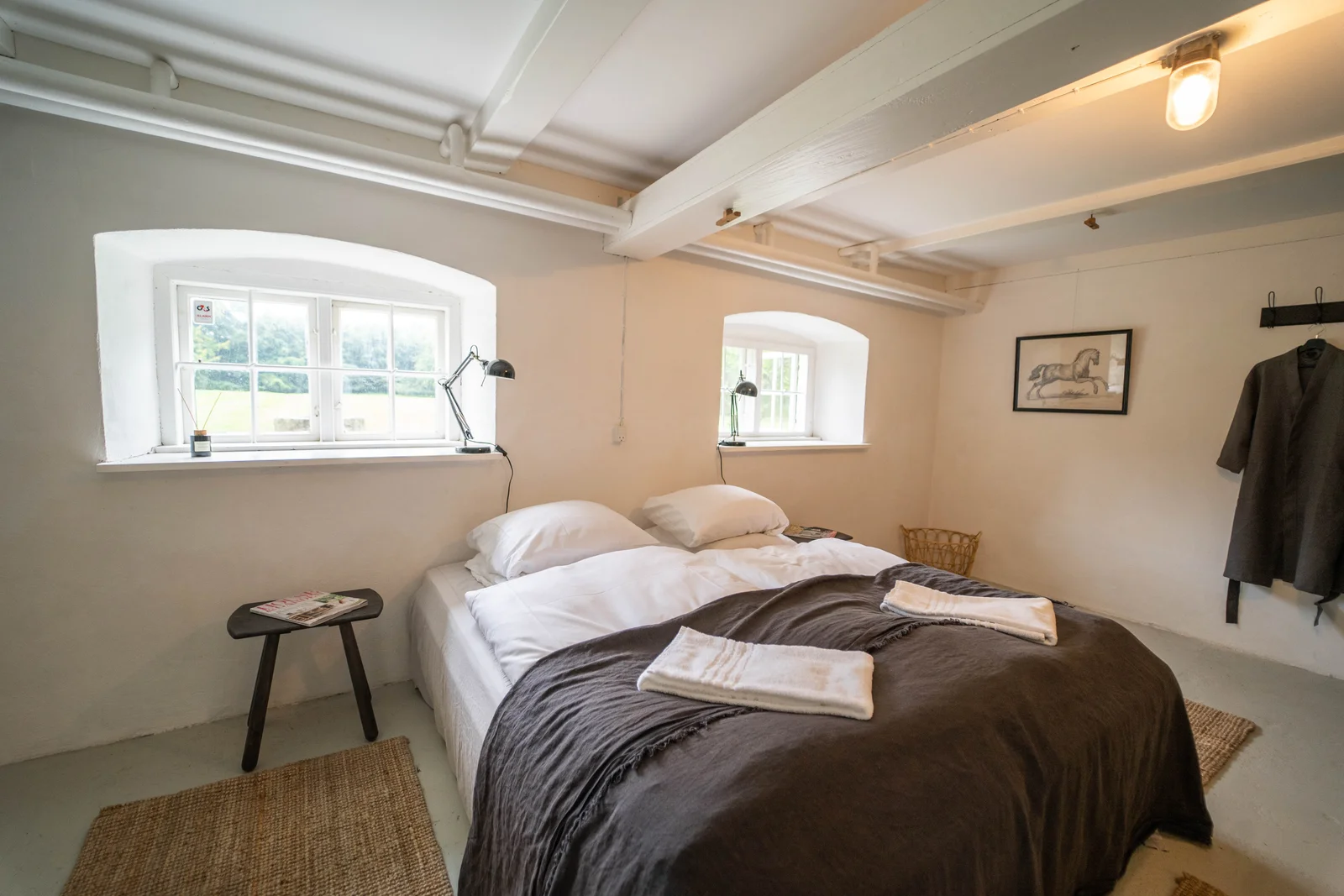 Gästezimmer im Herrenhaus von Gut Agerup mit zwei Fenstern und Handtüchern auf dem Bett