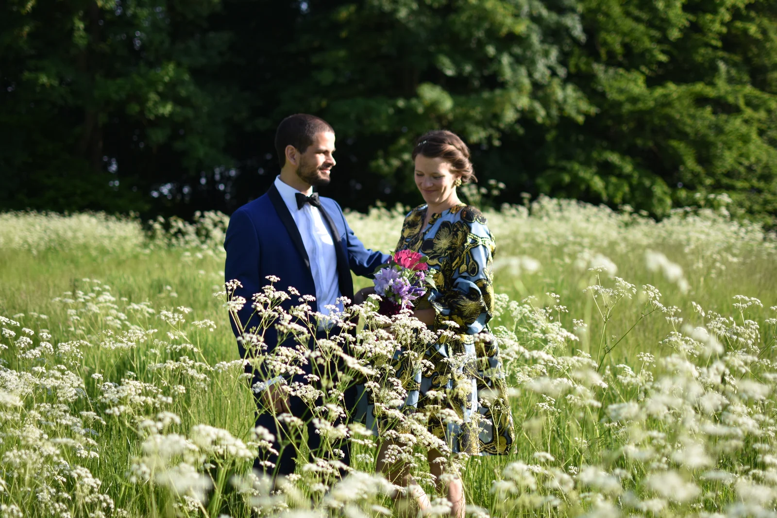 Ein Brautpaar mit Strauß in einer Wiese voller weißer Blumen auf Gut Agerup