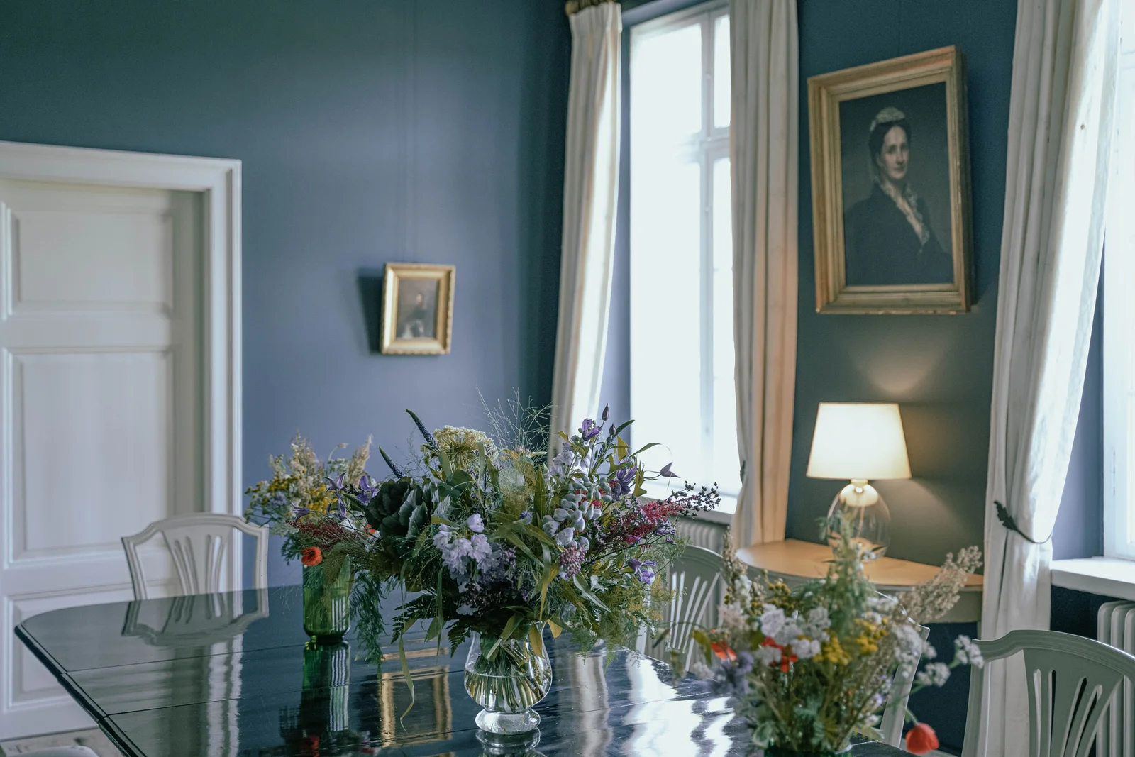 Das Speisezimmer von Gut Agerup mit Wildblumen auf der langen Tafel und einem Ahnenporträt