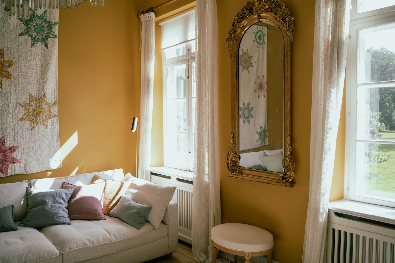 Vergoldeter Spiegel, Sternenquilt und Sofa im gelben Zimmer von Gut Agerup