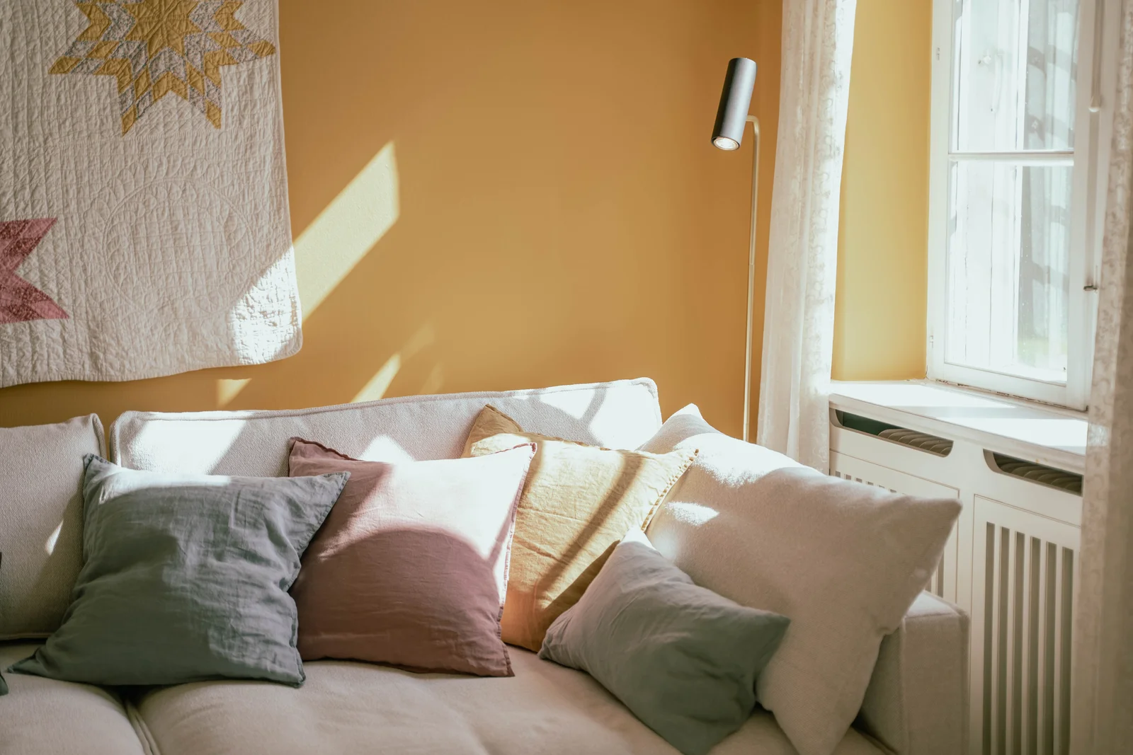 Sofa mit Kissen im Sonnenlicht im gelben Zimmer des Herrenhauses von Gut Agerup