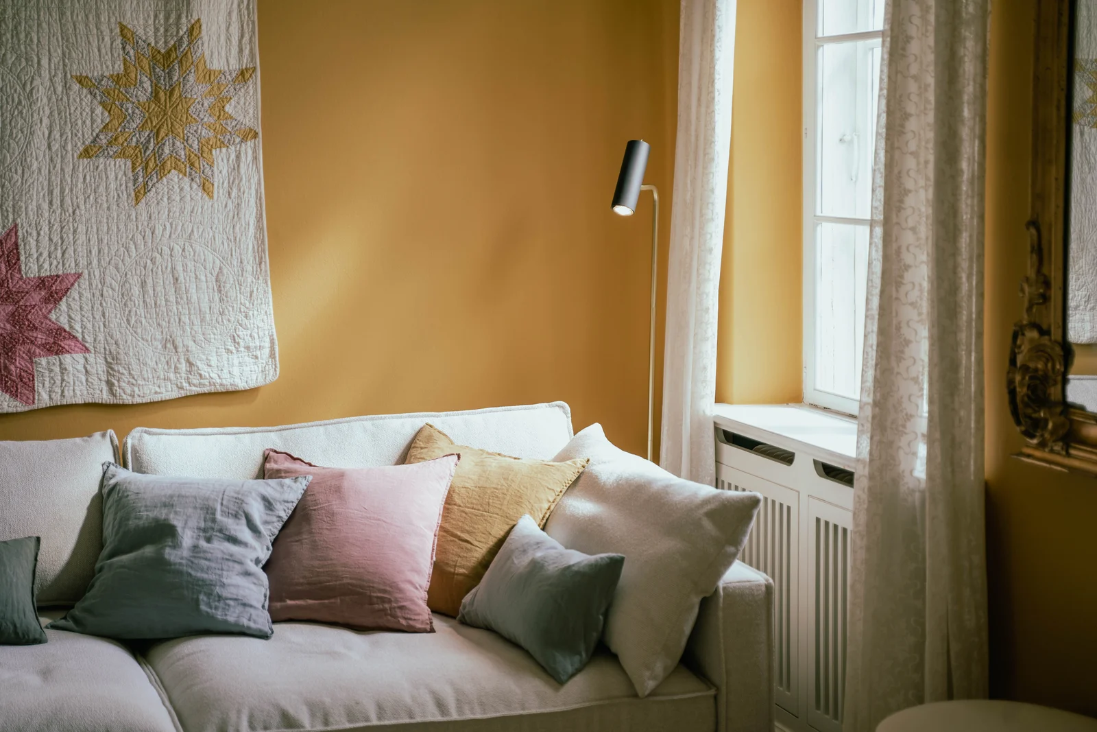 Das gelbe Zimmer von Gut Agerup mit Sternenquilt an der Wand und einem Sofa mit Kissen