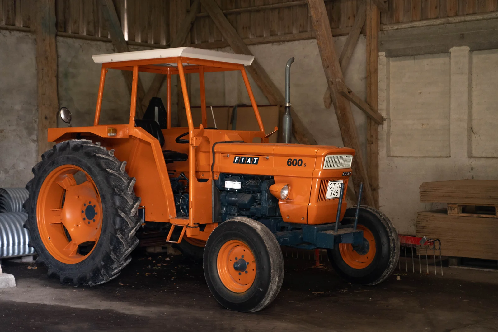 Gammel orange Fiat-traktor i en lade på Agerup Gods